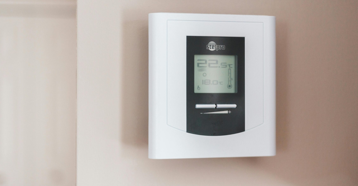 Close-up of a modern digital thermostat mounted on a wall, displaying temperature settings in Celsius.