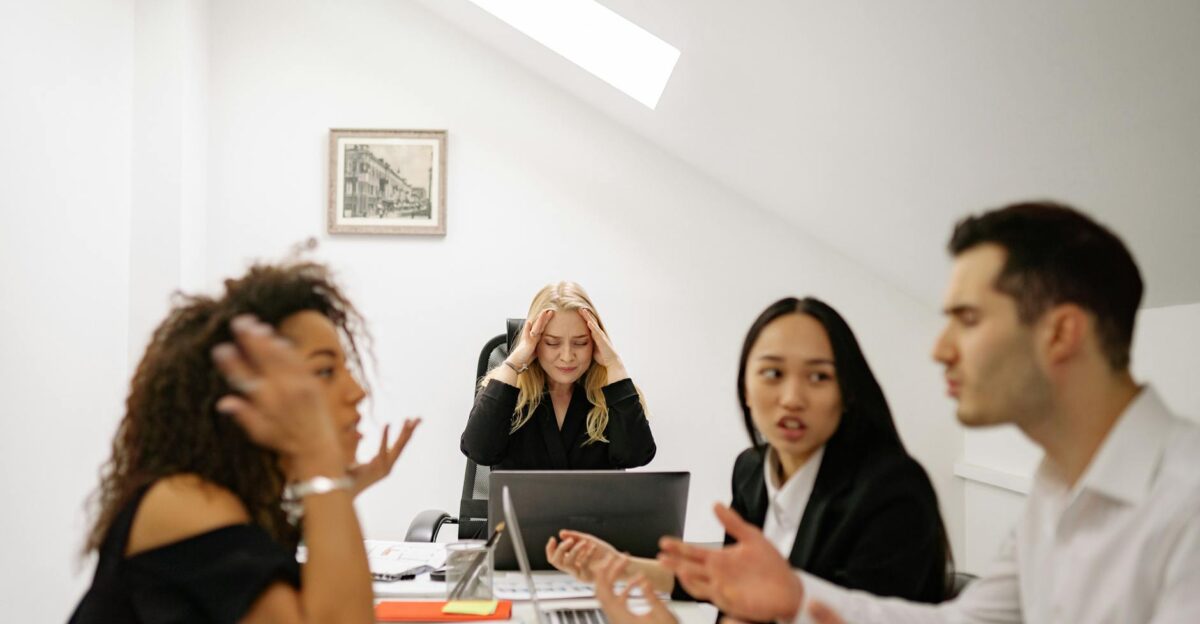 Colleagues in a heated discussion around a desk highlighting workplace stress and tension