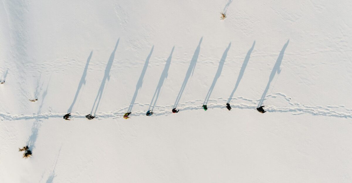 Aerial shot of hikers casting shadows on a snowy field in Rakhivs kyi Ukraine