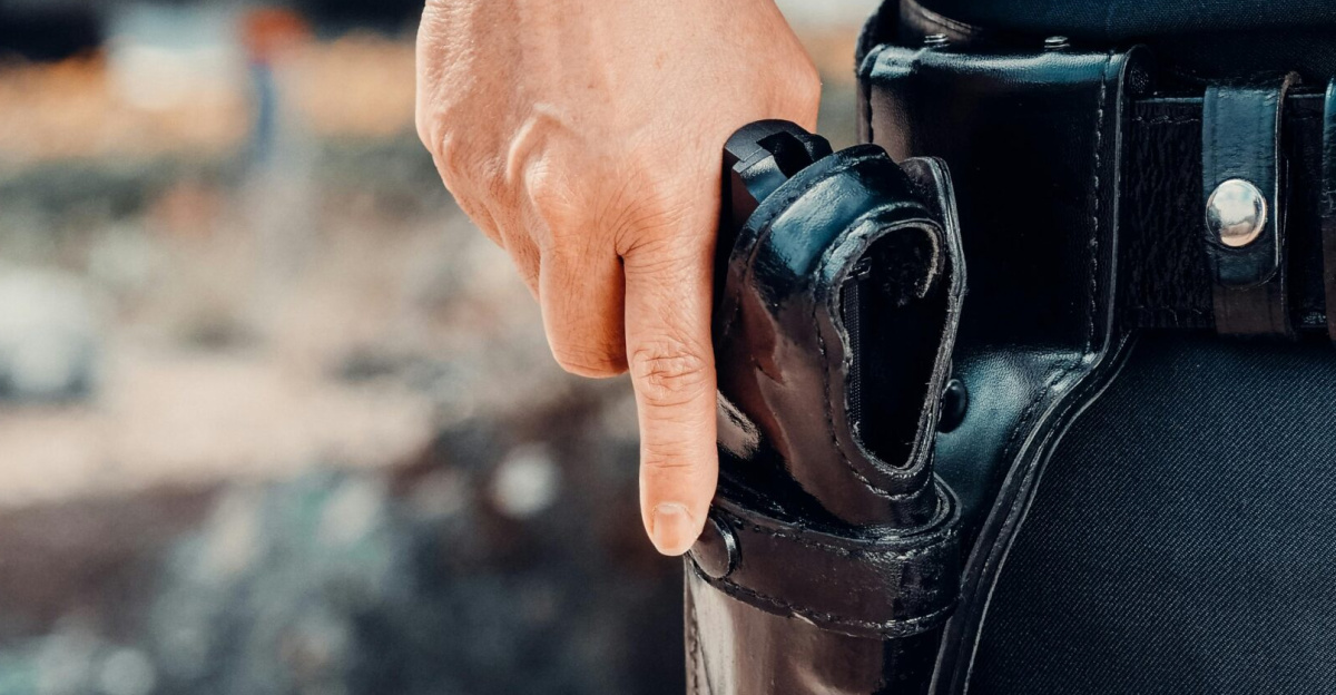 Close-up of a police officer's hand on a holstered gun, emphasizing security and law enforcement.