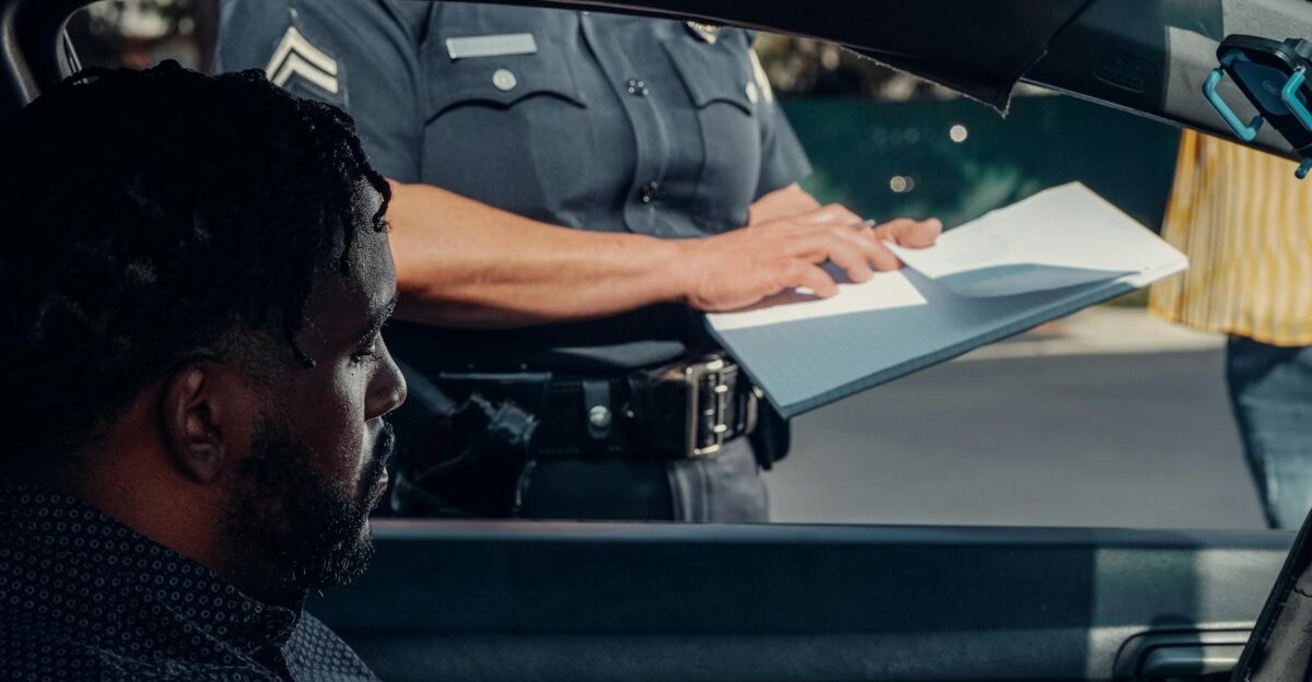 A police officer issues a traffic ticket to a man in a car Close-up view of the interaction through the window