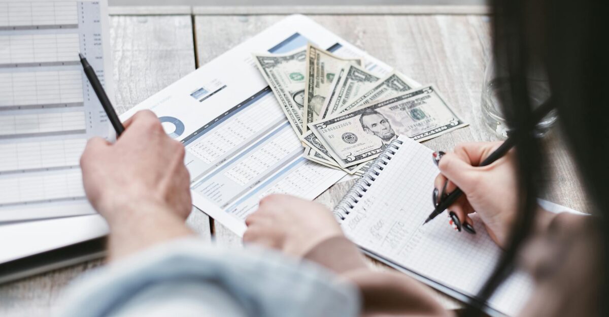 Two people working on financial documents and dollar bills for budgeting