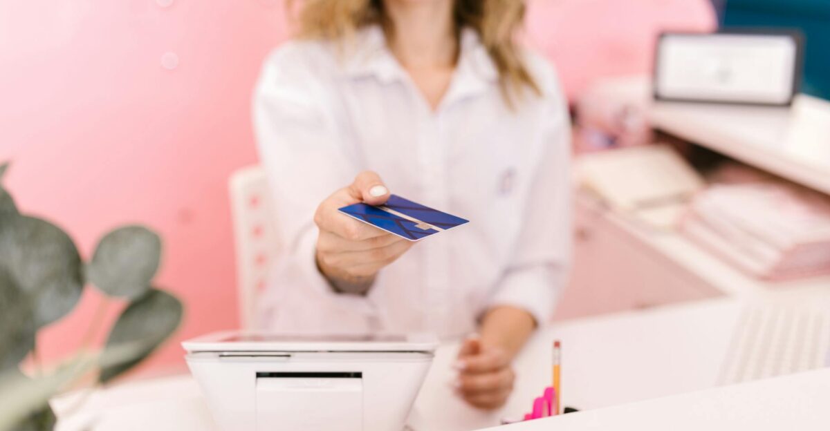 Blurred hands offering a credit card to a cashier at a modern retail counter