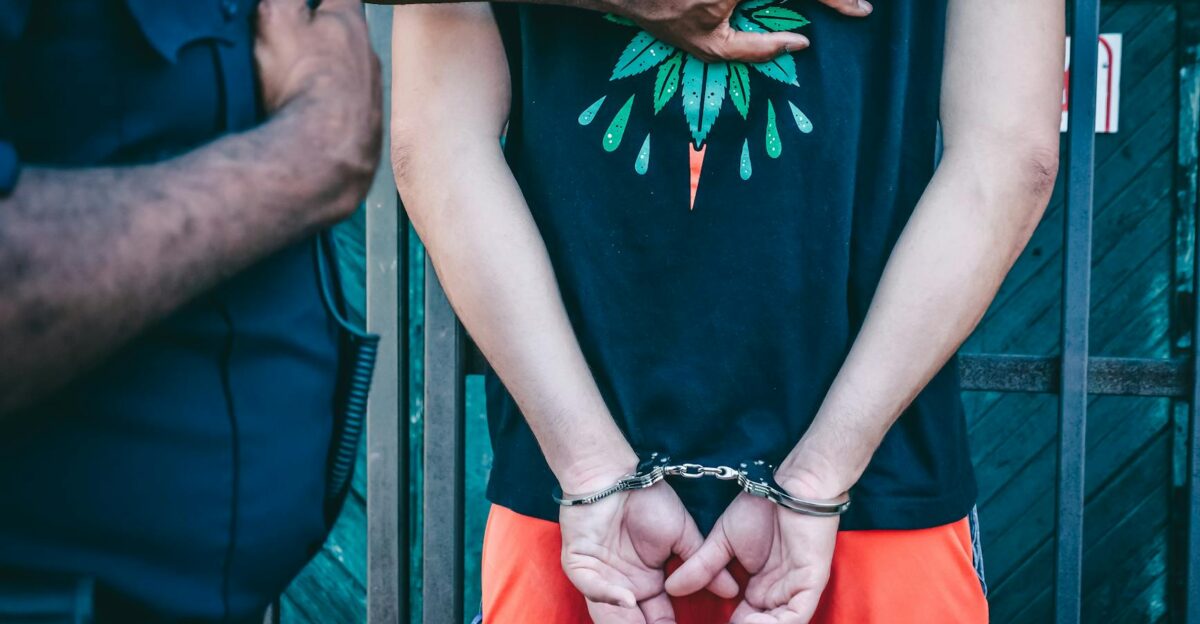 Close-up of a handcuffed person under arrest by a police officer outdoors