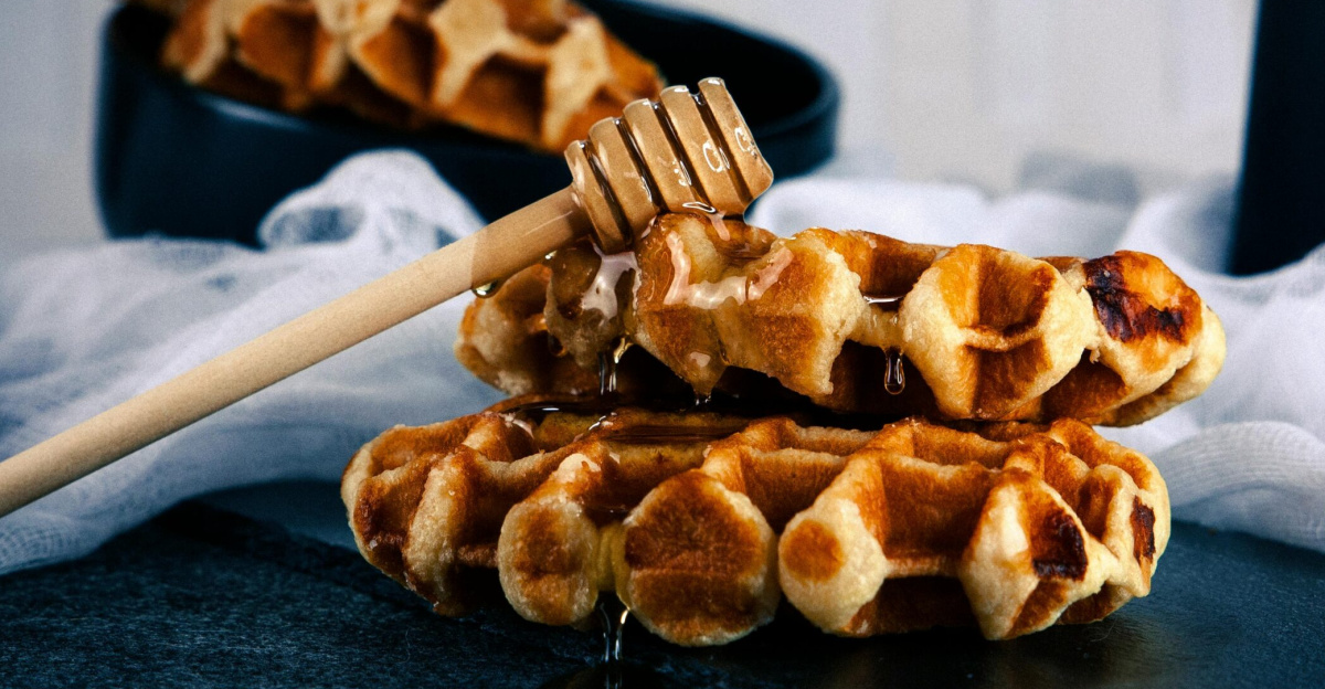 Tasty Belgian waffles drizzled with honey on a black plate, perfect for breakfast.