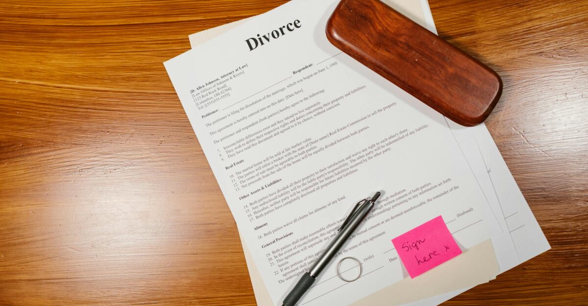 Flat lay of divorce papers with a pen and ring on a wooden table for legal themes