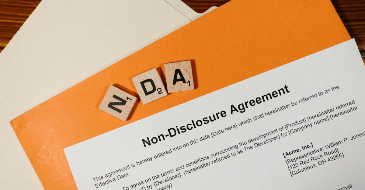 Top view of a Non-Disclosure Agreement with NDA in Scrabble tiles emphasizing confidentiality