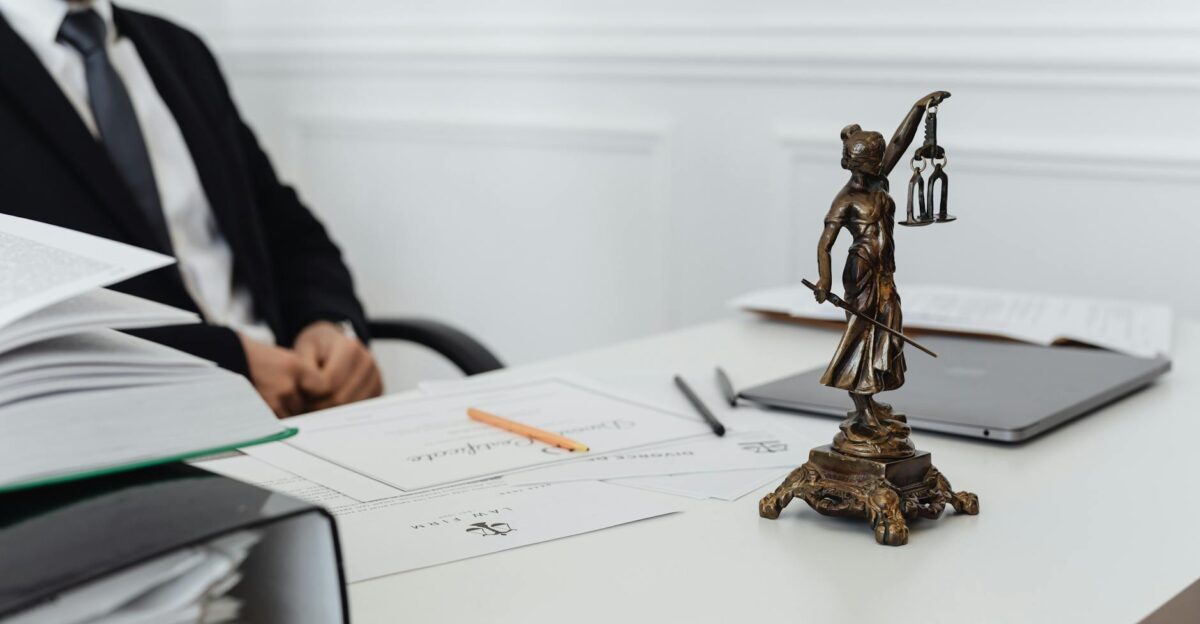 A legal professional s workspace featuring Lady Justice statue documents and a laptop