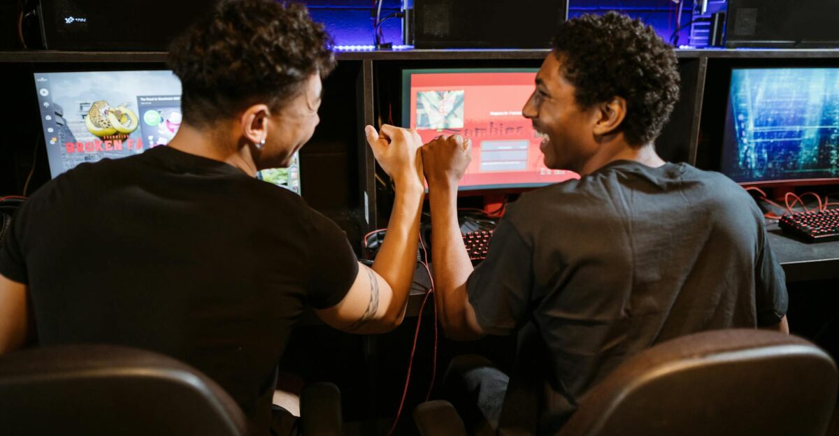 Two male friends enjoying a victory in a gaming competition indoors showcasing teamwork and friendship