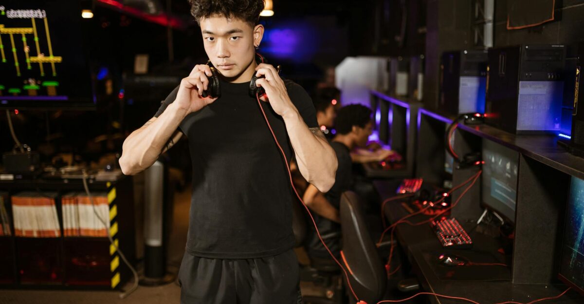 A serious young man in a gaming lounge with headphones embodying the modern e-sports culture