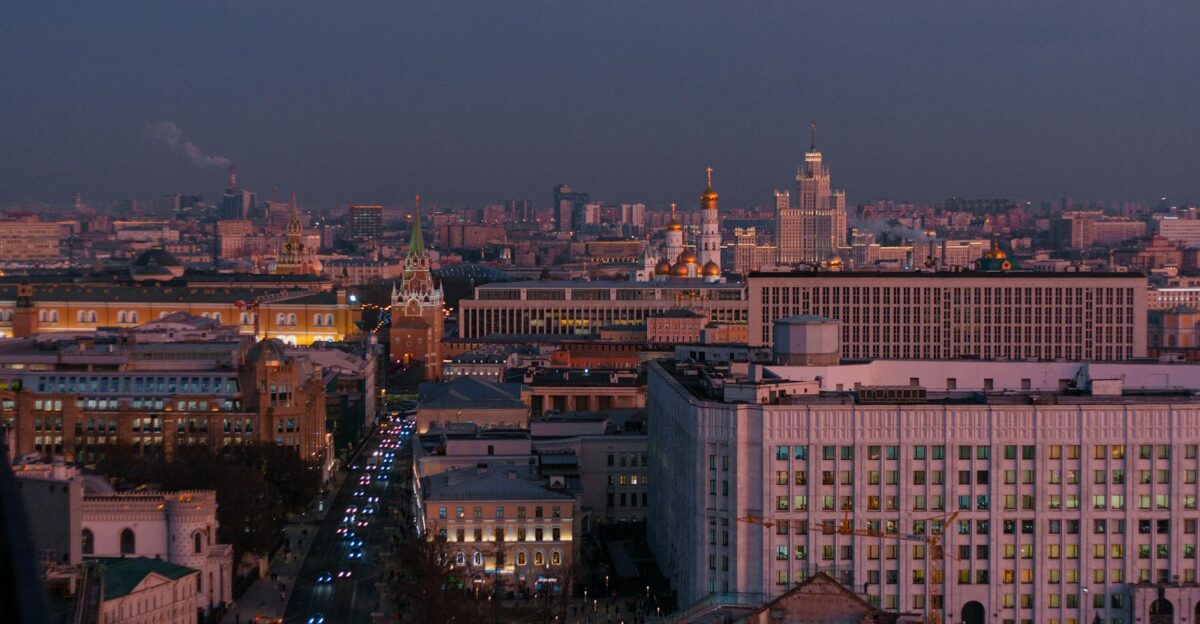 A stunning aerial view of Moscow cityscape during twilight featuring the illuminated Kremlin and bustling streets
