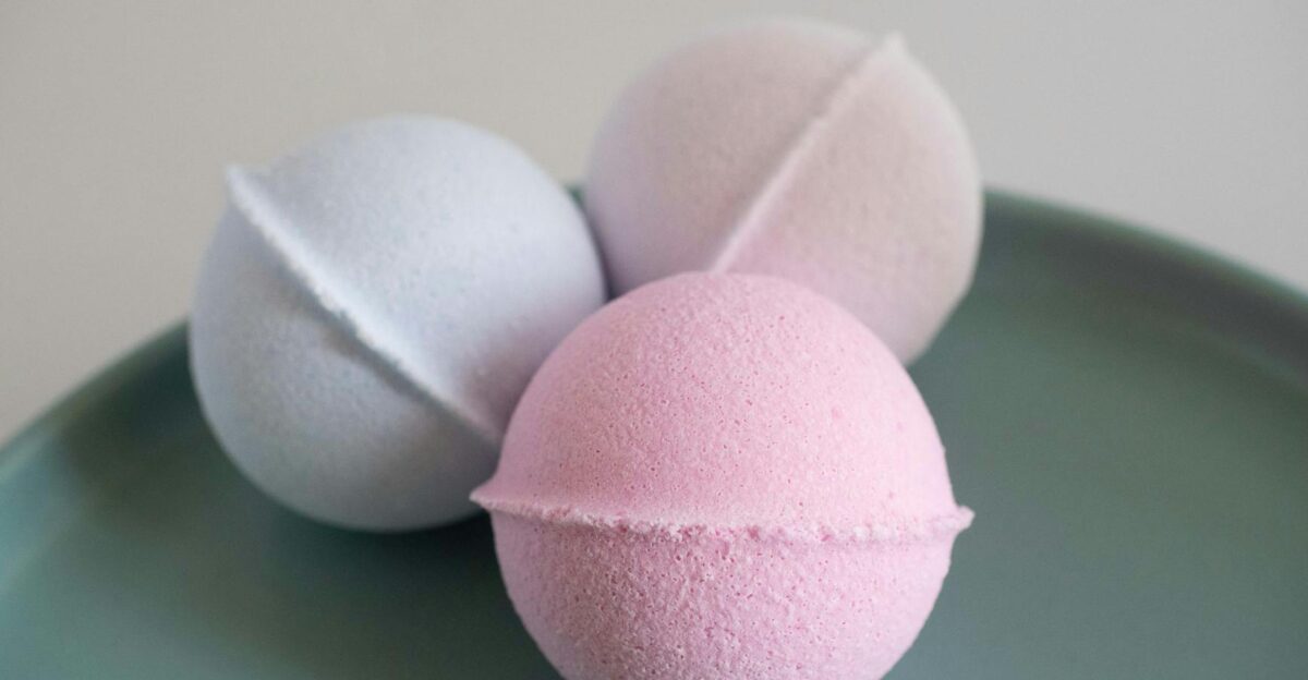 Three vibrant bath bombs displayed on a green ceramic plate perfect for a spa setting