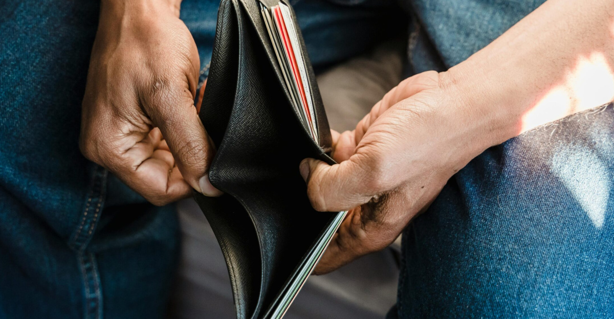 Close-up of a man holding an empty wallet, symbolizing financial crisis and hardship.