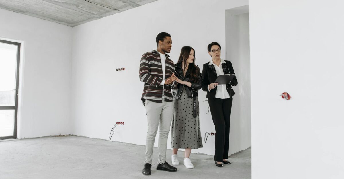 Real estate agent with clients exploring an unfinished apartment interior
