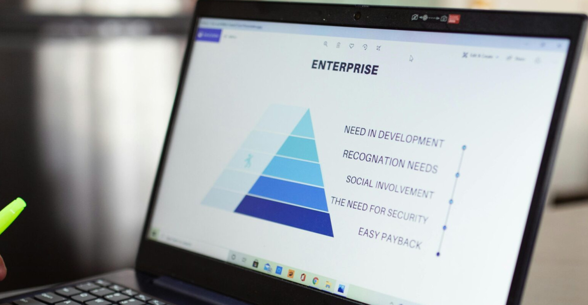 Person analyzes business data on laptop, using pyramid chart and financial reports.