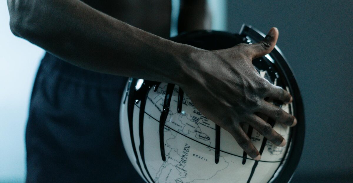 A hand holding a globe dripping with oil symbolizing pollution and fossil fuels