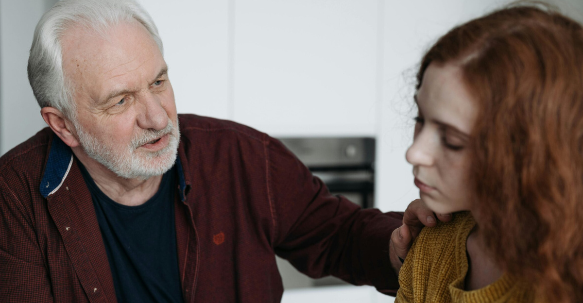 An elderly man consoles a young woman indoors, expressing empathy and understanding.