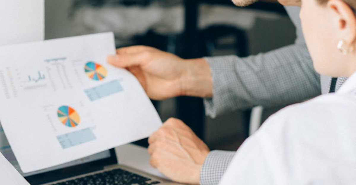 Two business professionals reviewing financial charts and graphs in a modern office setting