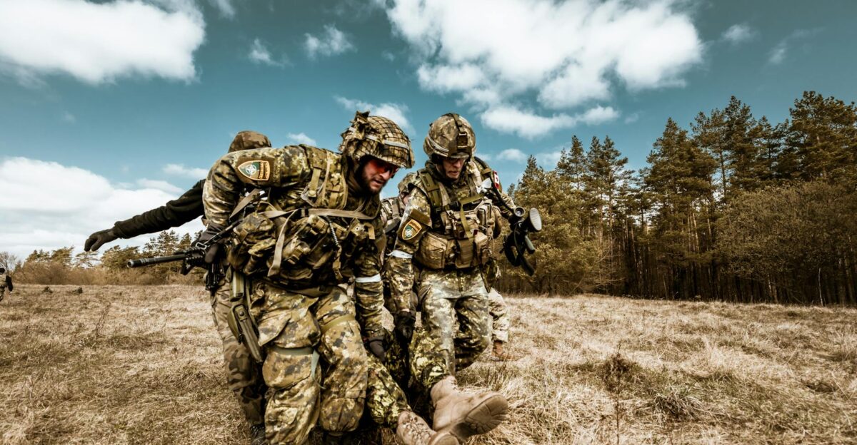 Military personnel actively engaged in outdoor rescue operation on grassy field showcasing teamwork and bravery