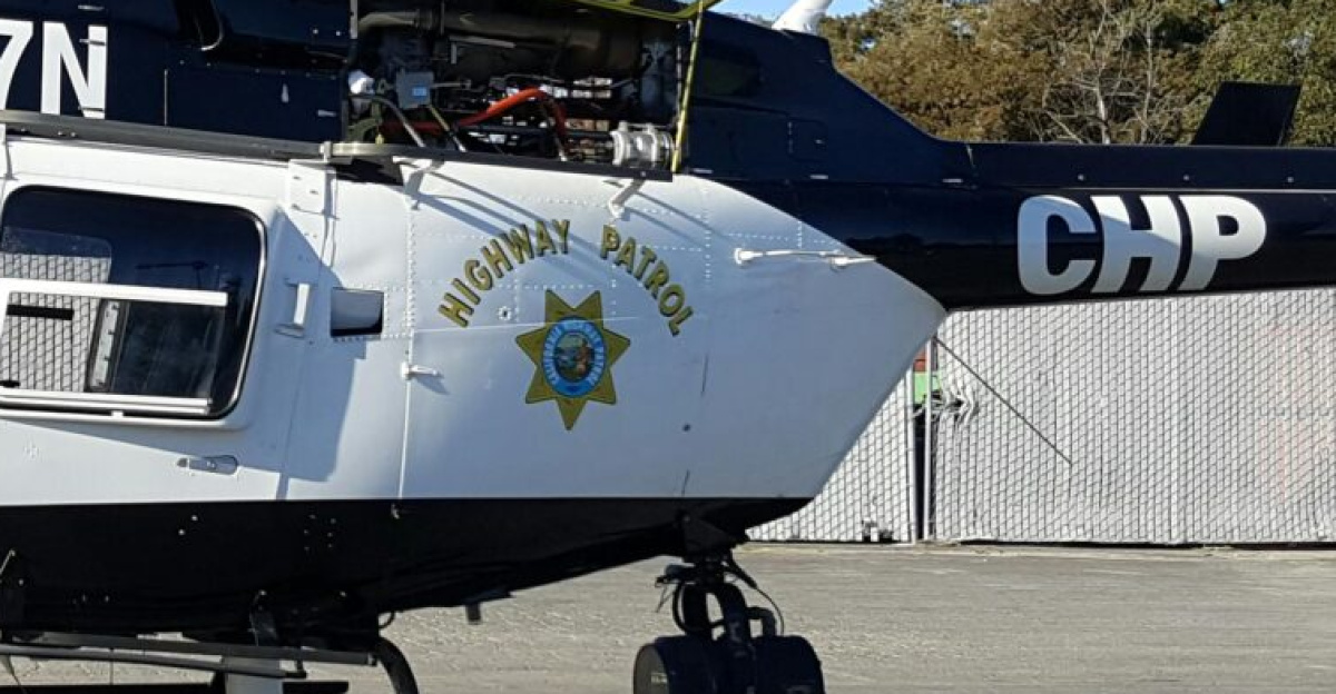 Police helicopter on display with officers standing beside it in an outdoor setting.