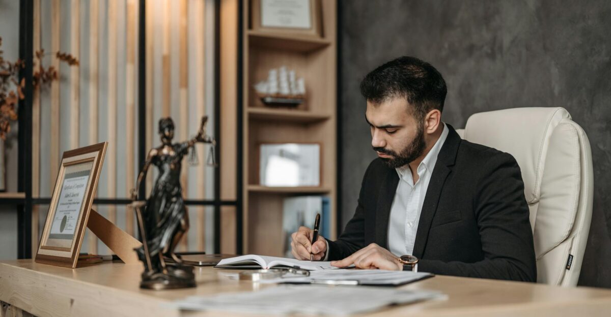 A focused lawyer in an office setting writing and reviewing legal documents symbolizing expertise and professionalism