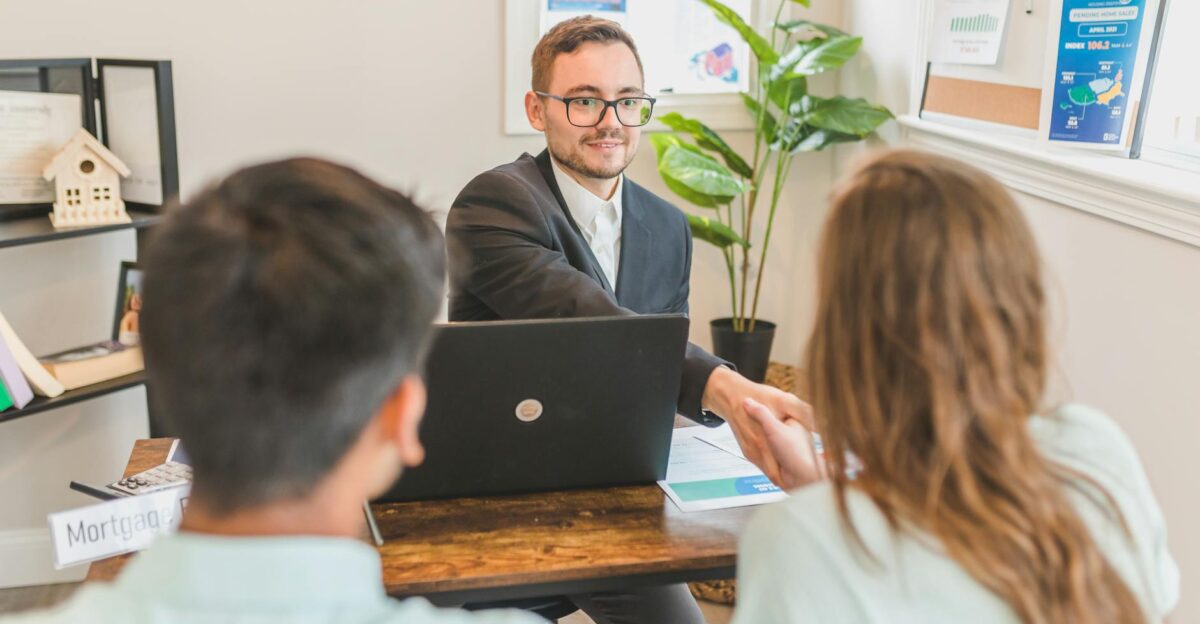 A mortgage broker meeting clients in an office discussing agreements and loans