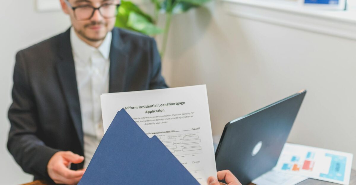 Mortgage broker and client discussing loan application with documents on table