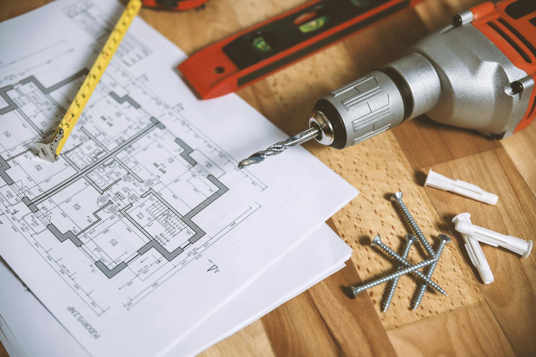 Close-up of construction blueprint with tools like drill and screws on a wooden table