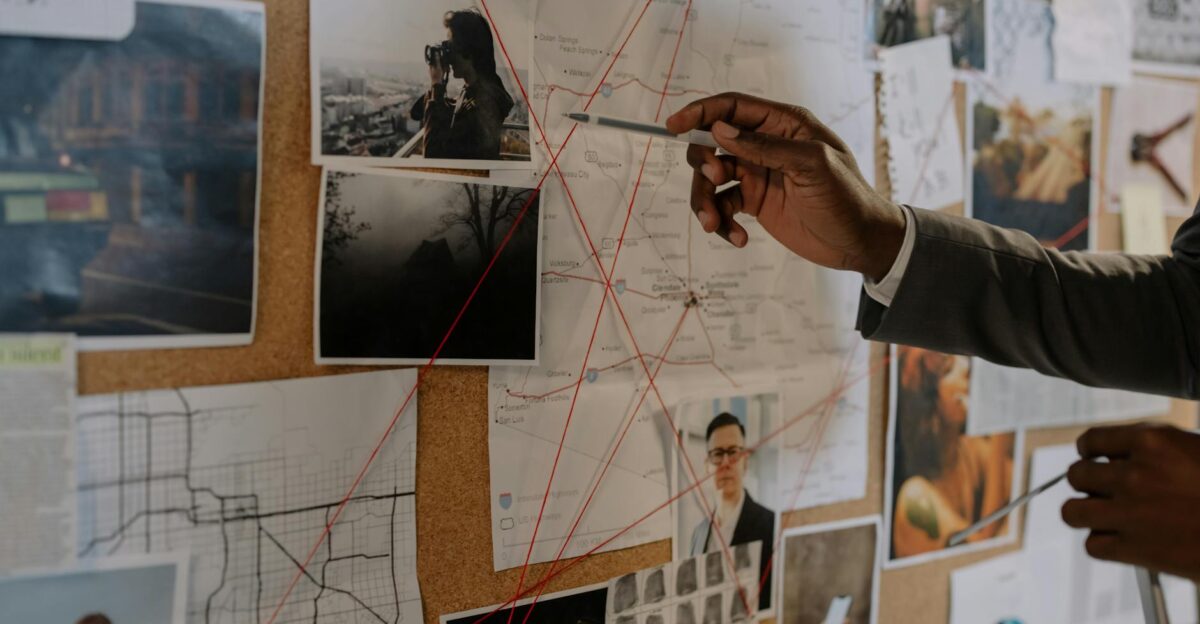 Detective examines a corkboard with maps and photos to solve a mystery
