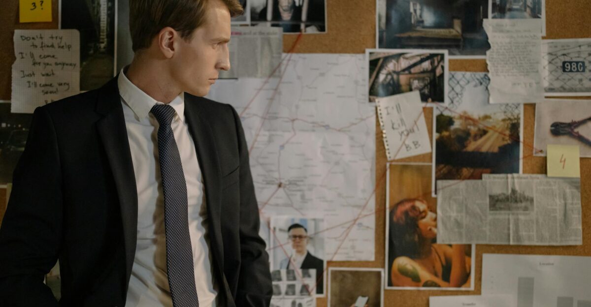 Detective in suit examining evidence on cork board during investigation process