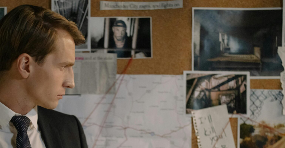 Detective in suit examining evidence on cork board during investigation process.