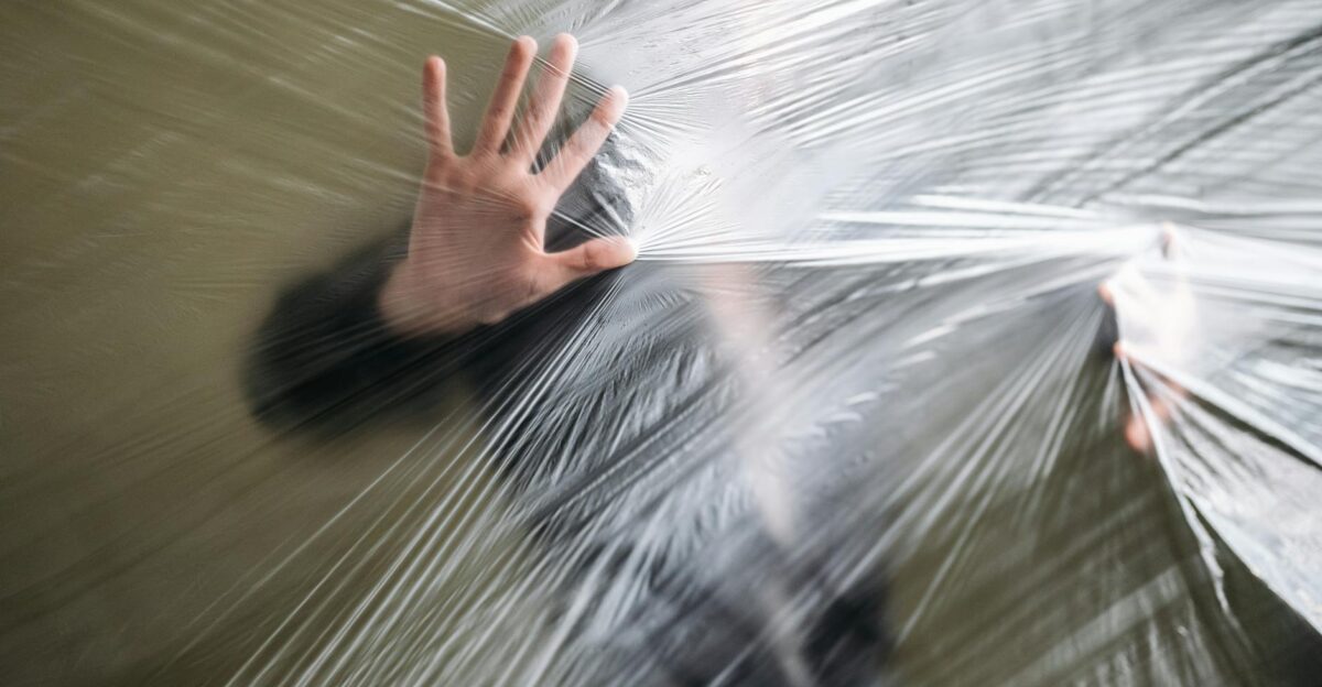 A person pushing against a plastic sheet representing entrapment and pollution