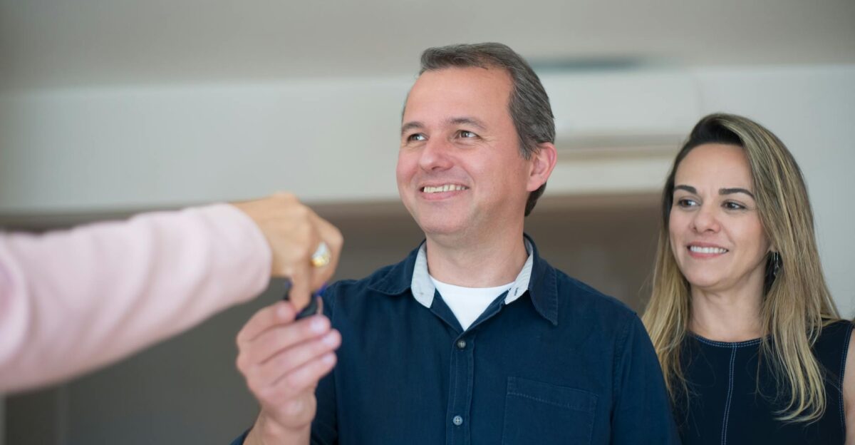 Smiling couple receiving keys celebrating new home purchase indoors