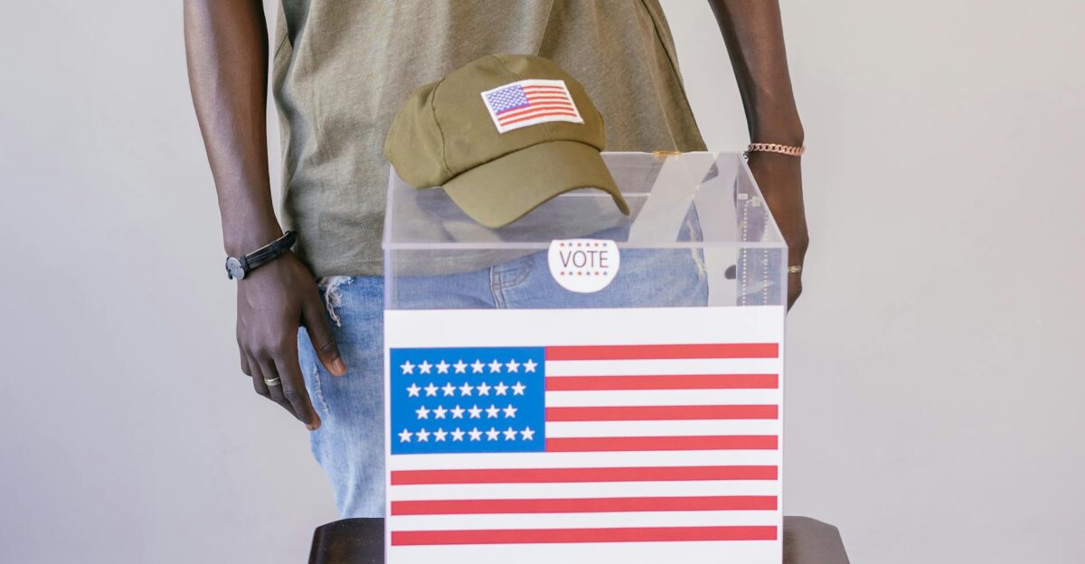 Adult voter standing by a ballot box with American flag symbolizing democracy and election participation