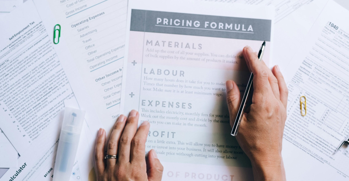 Hands organizing business documents and pricing formula papers on an office desk.