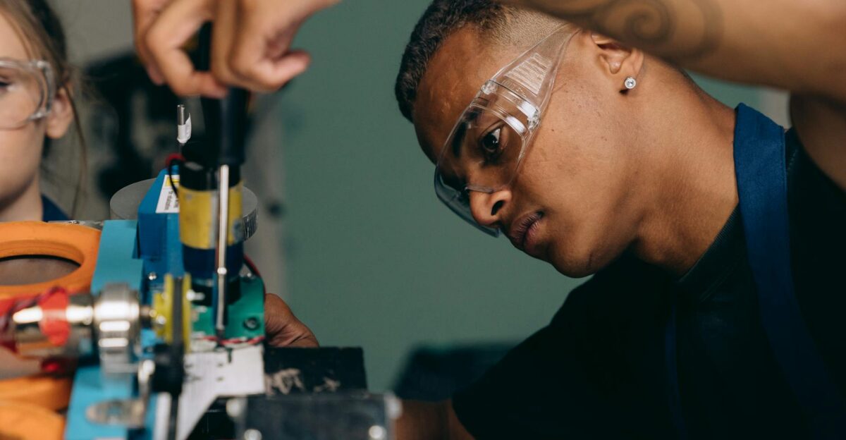 Two young technicians focus on electronic equipment assembly in a workshop setting