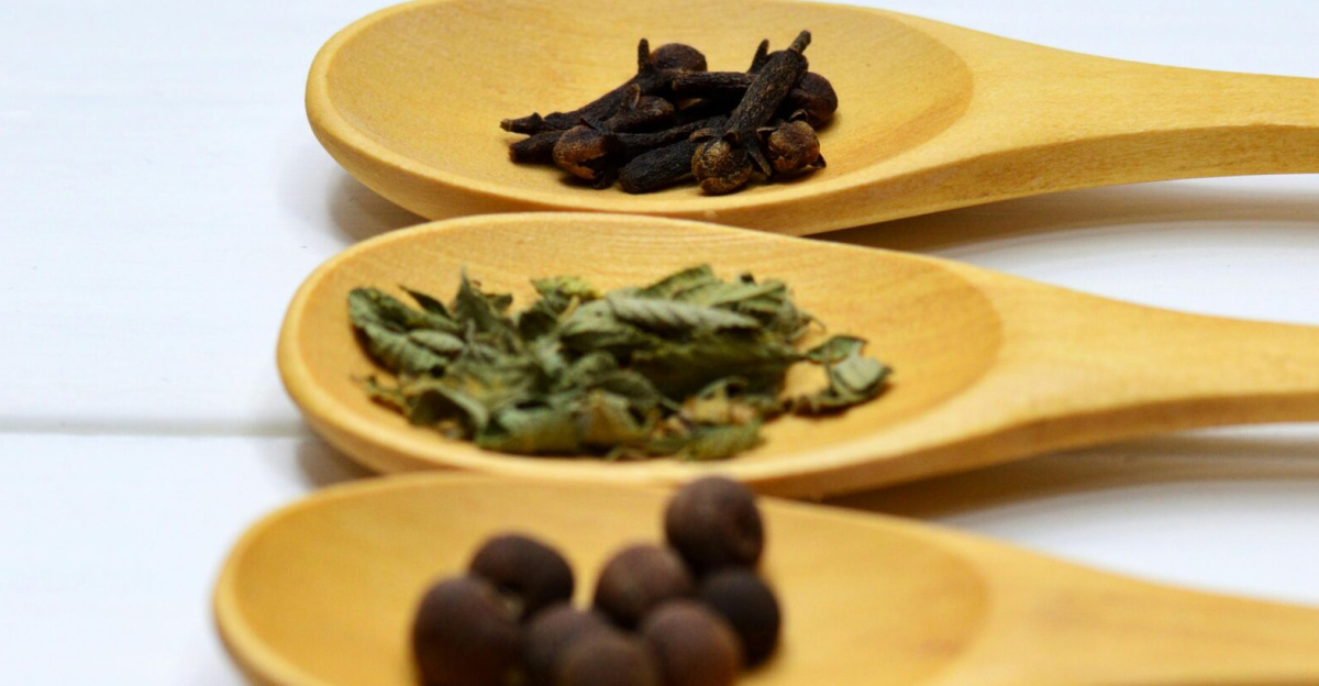 A variety of spices arranged neatly on wooden spoons over a white surface, providing culinary inspiration.