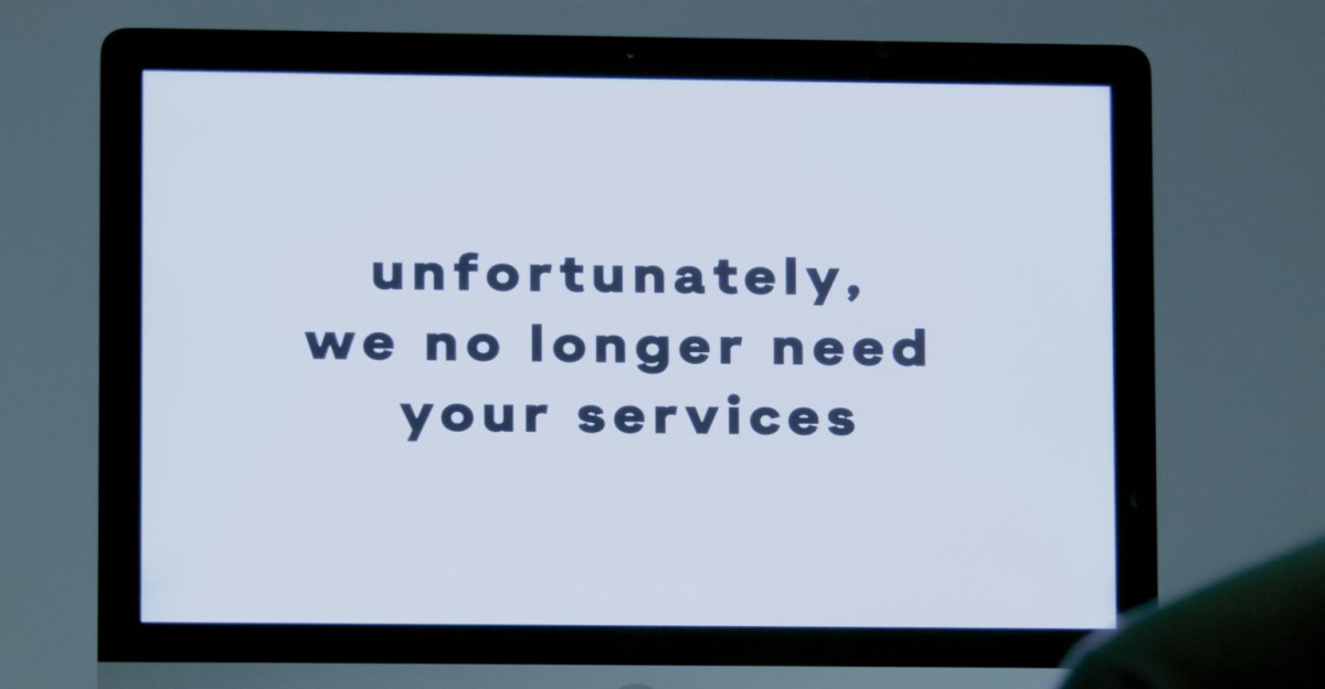 A computer screen displays a termination message, indicating job loss or unemployment.