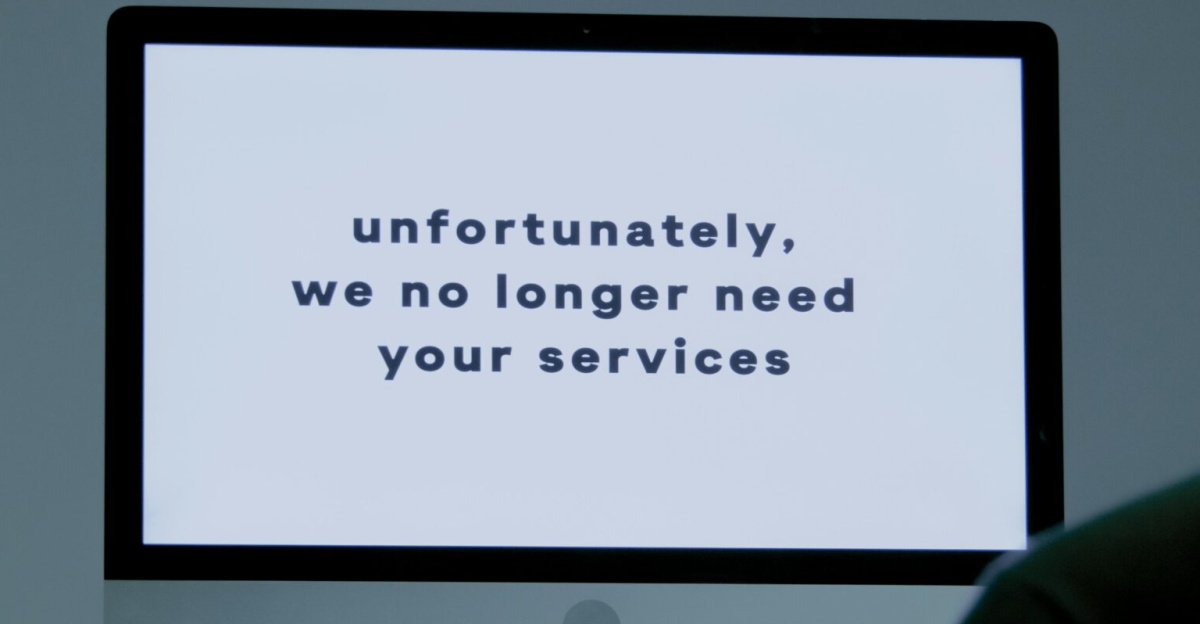 A computer screen displays a termination message, indicating job loss or unemployment.