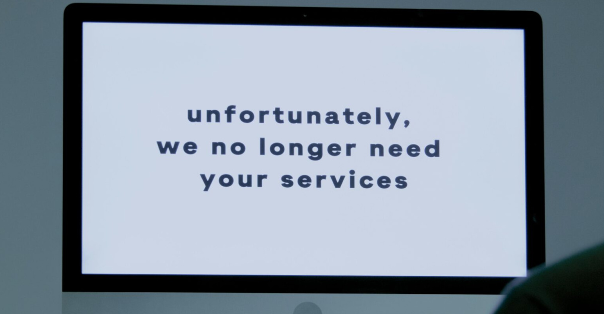 A computer screen displays a termination message, indicating job loss or unemployment.