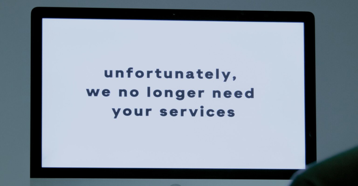 A computer screen displays a termination message, indicating job loss or unemployment.