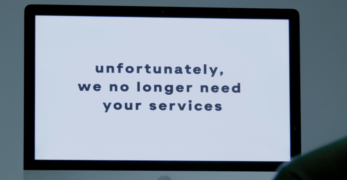 A computer screen displays a termination message, indicating job loss or unemployment.