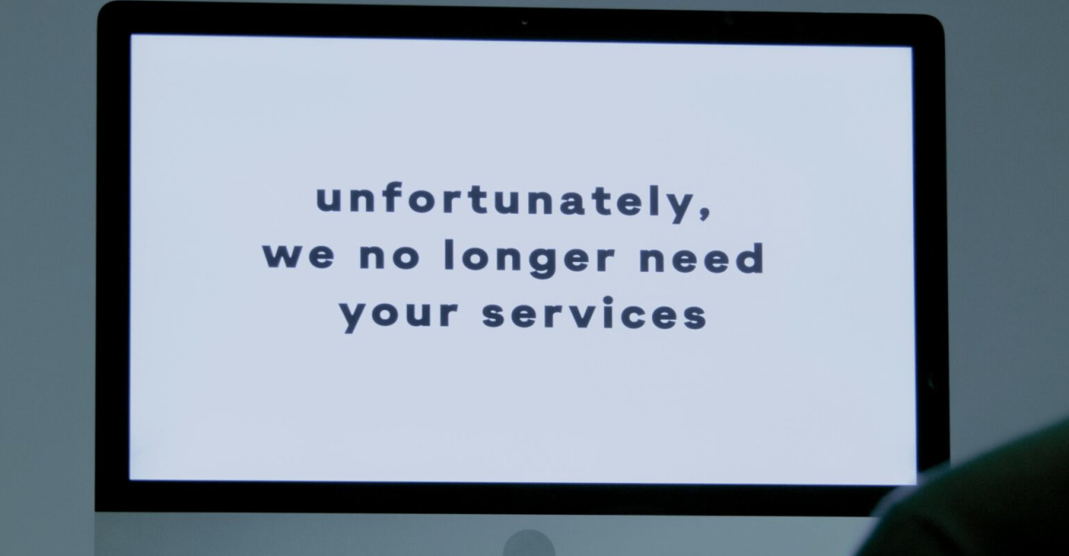 A computer screen displays a termination message, indicating job loss or unemployment.