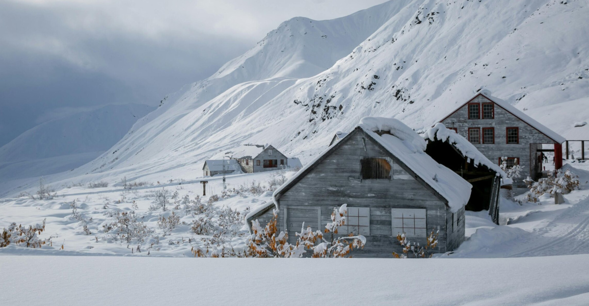Serene winter landscape featuring snow-covered mountains and rustic houses in Palmer, Alaska.