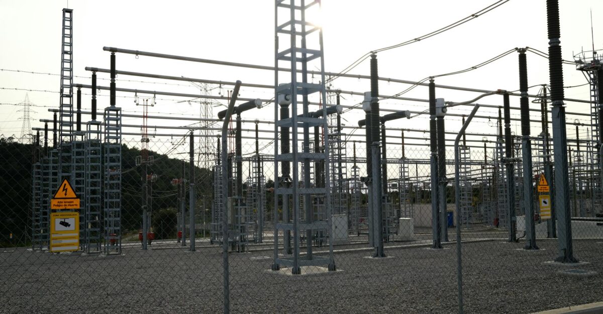 Outdoor electrical power substation with high voltage equipment and safety signs surrounded by fencing