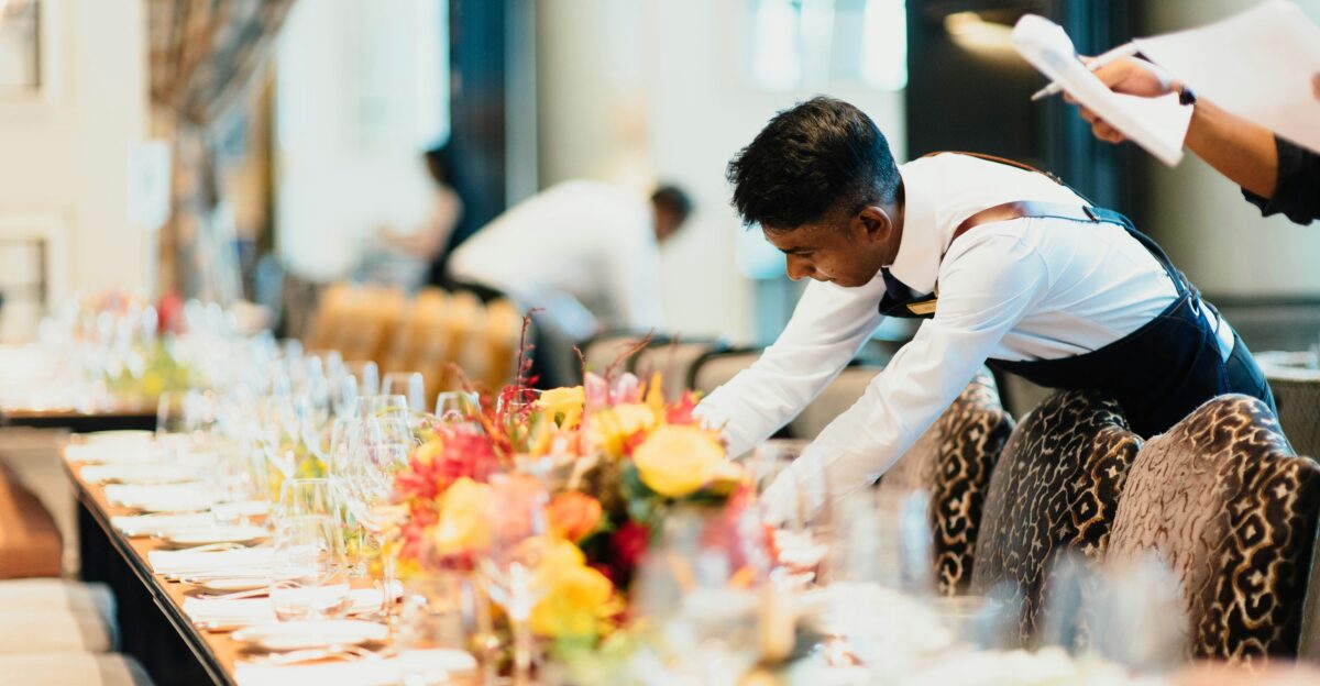 man in white top standing next to table