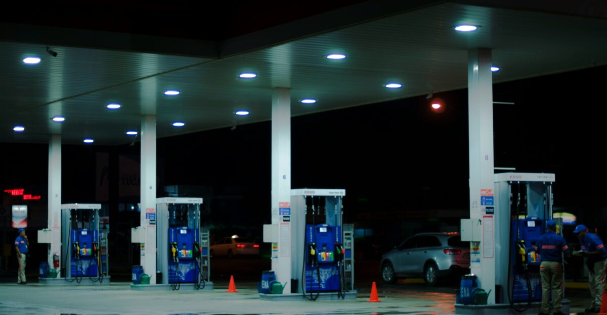 person taking a photo of blue and white gasoline station