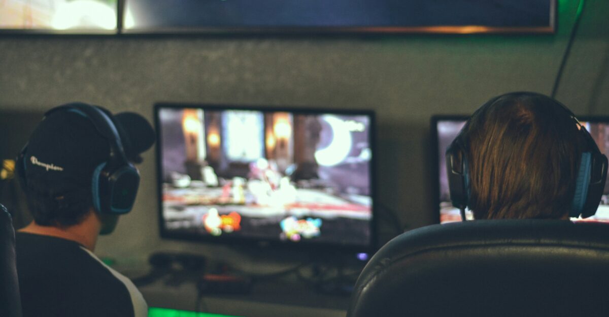 selective focus photography of two persons playing game in front of monitors