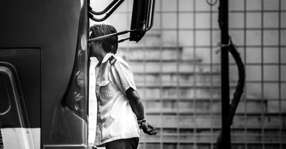 grayscale photography of man standing beside bus