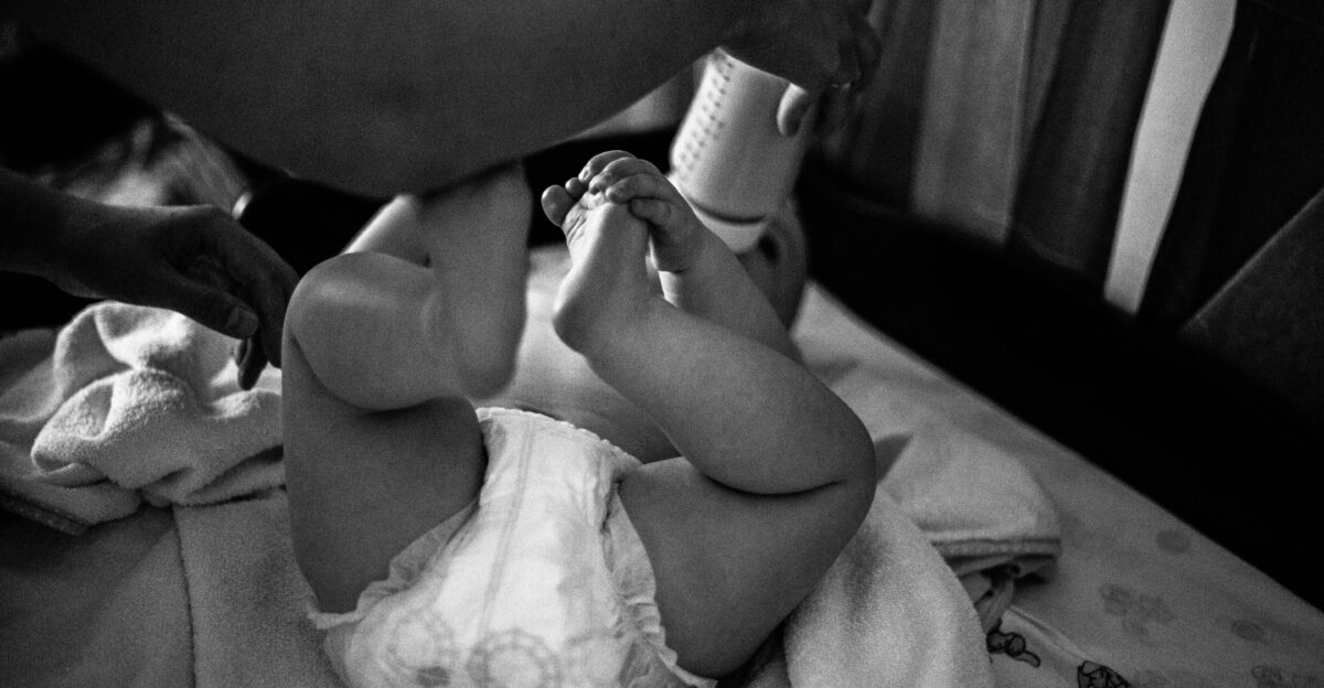 a black and white photo of a baby on a bed